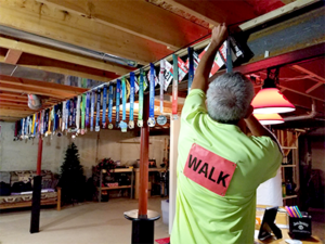 Kevin hanging competitive walking medals on bar in basement.