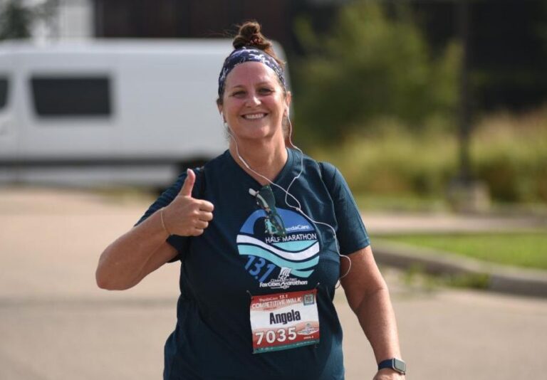 Fox Cities Marathon woman competitive walking with thumbs up.