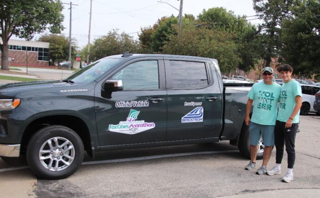 Fox Cities Marathon proud sponsor Bergstrom Automotive's black truck with two volunteers.