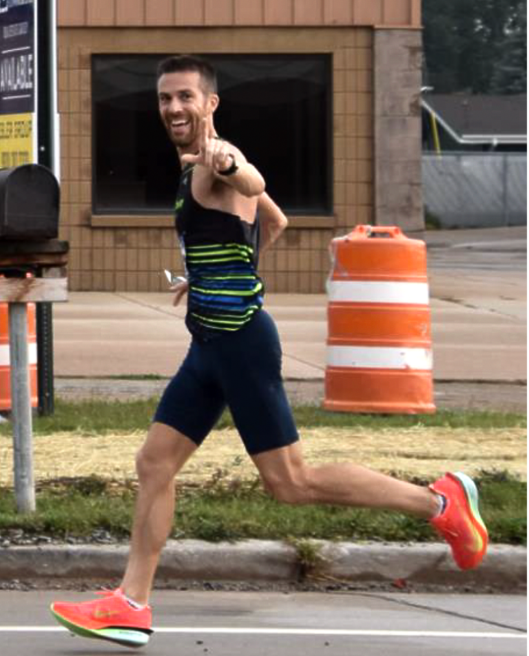 Fox Cities Marathon runner John Hollister running, pointing at camera.