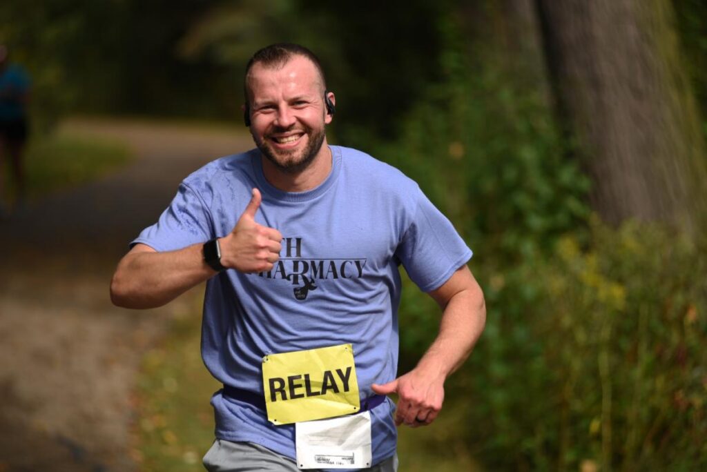 Fox Cities Marathon man in blue shirt running the relay marathon giving a thumbs up.
